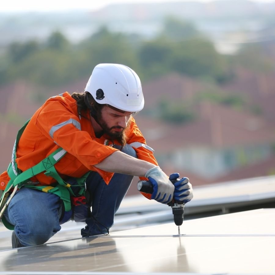Construction worker installing a flat roofing system on a modern home.