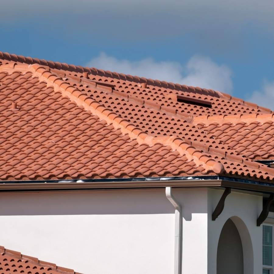 Worker completing tile roofing installation on upscale Hidden Hills home.